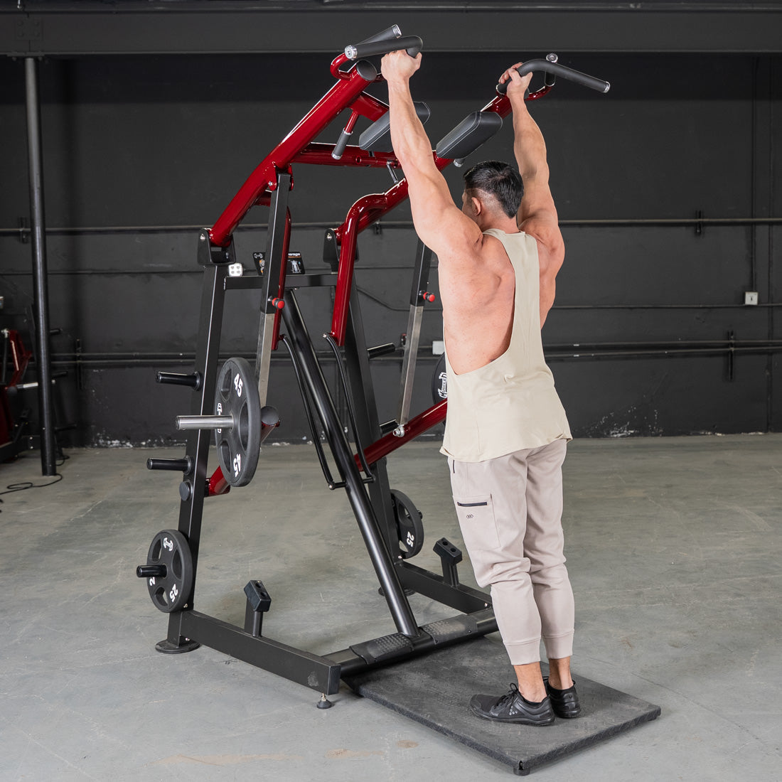 Man performing a calf raise on a red and black Viking press machine with weight plates.