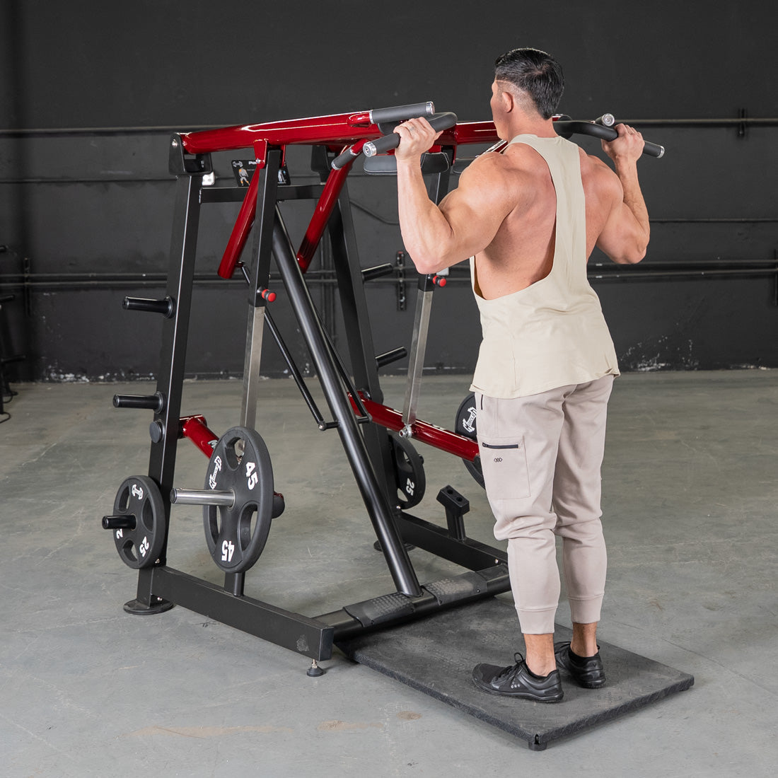 Man using a red and black Viking press machine with weight plates in a gym.