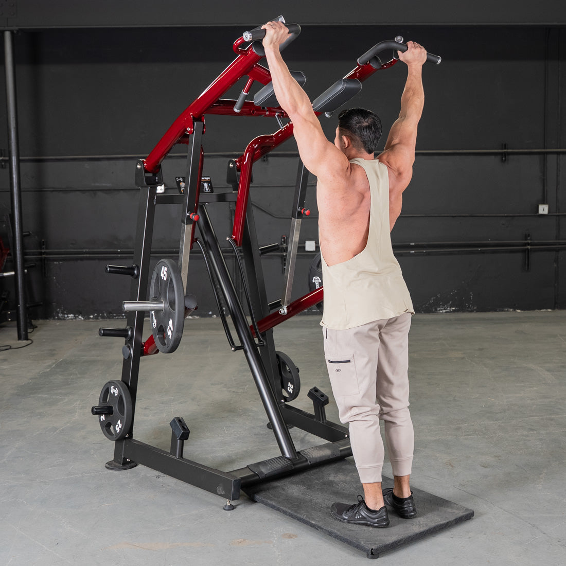 Man using a red and black Viking press machine with weights in a gym.
