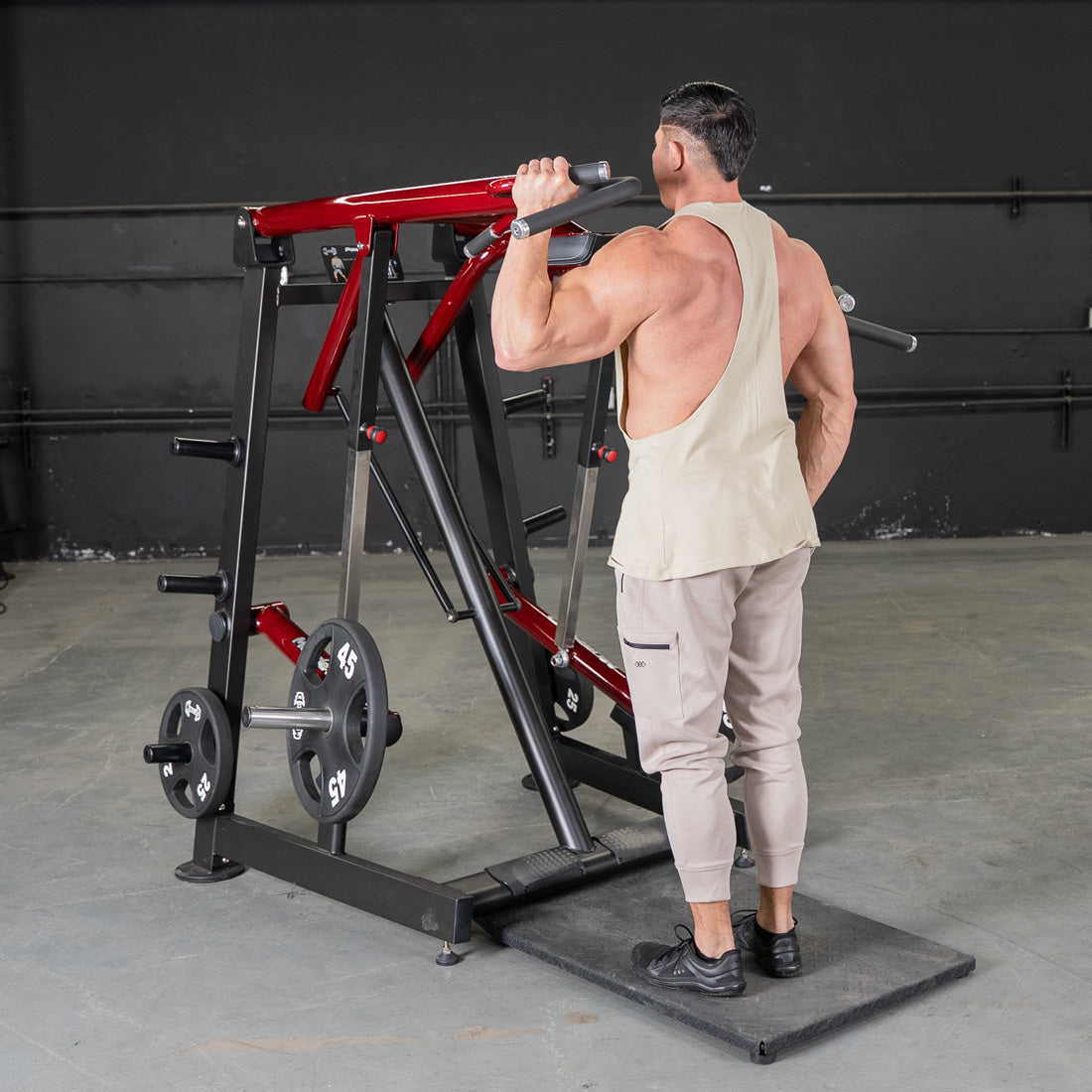 Man using a red and black Viking press machine with weight plates in a gym.