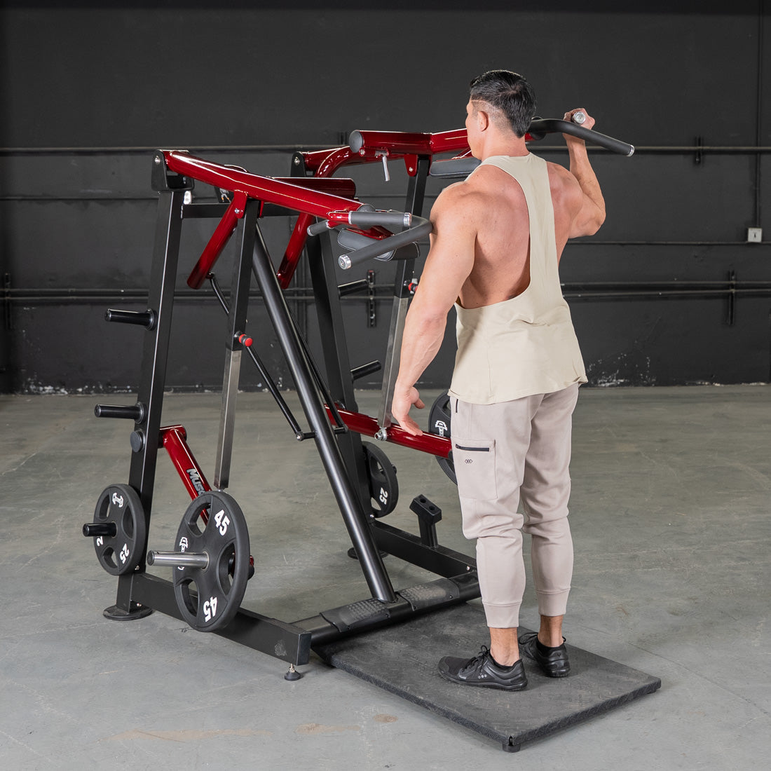 Man using a red and black Viking press machine with weight plates in a gym.