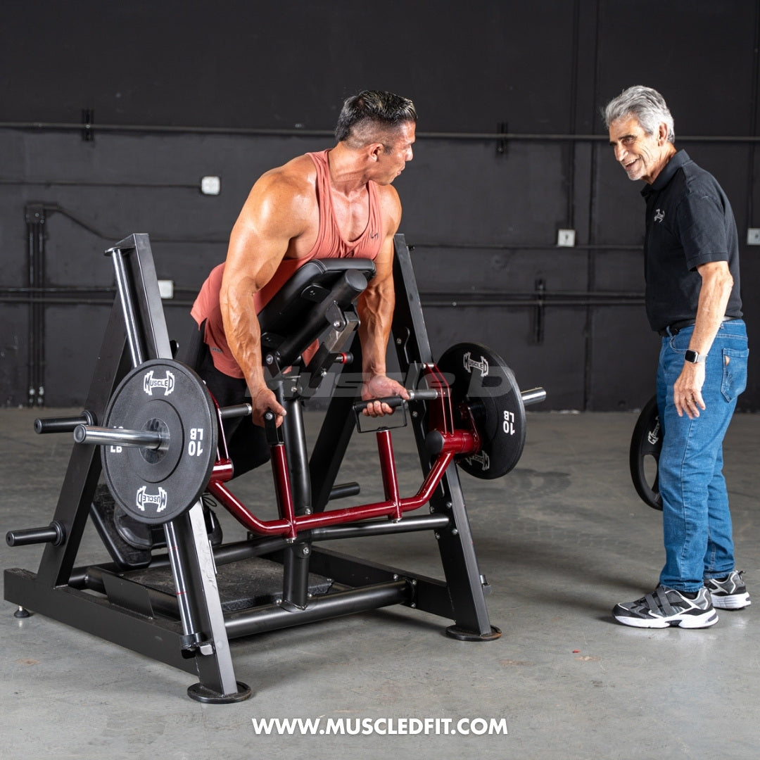 Man using a chest-supported linear bearing row machine with a trainer watching.