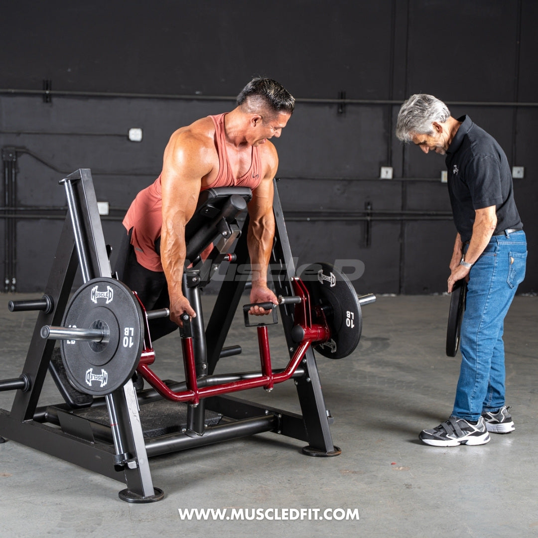 Man using a chest-supported linear bearing row machine with another man adding weight plates.