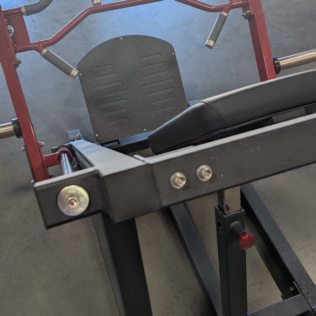 Close-up of a linear bearing row machine with a black footplate, seat, and red frame.