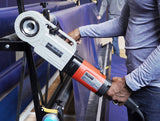 Hand holding an orange and gray power winder attached to a blue gym floor cover storage rack