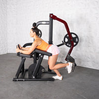 Thumbnail for Woman using a plate-loaded glute kickback machine with a 45lb weight plate.