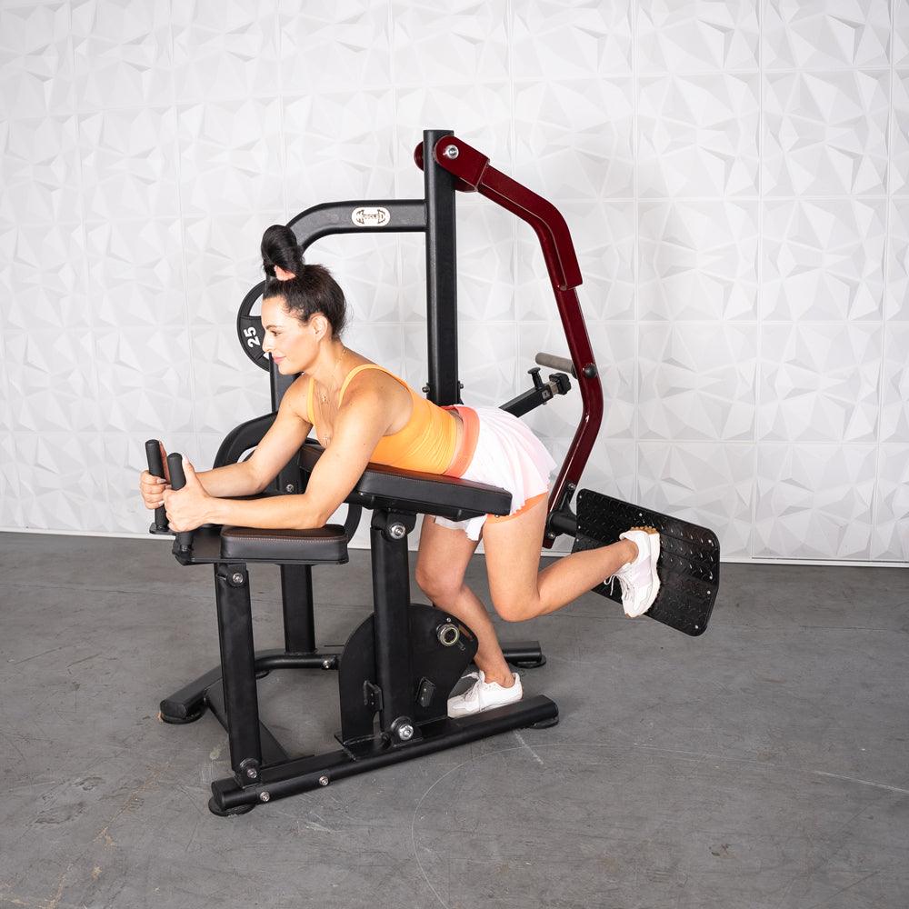Woman using a black and red glute kickback machine with a weight plate.