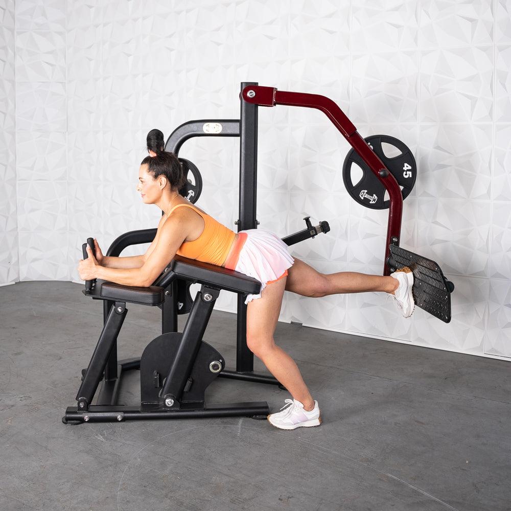 Woman using a black and red glute kickback machine with a 45lb weight plate.