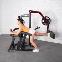 Thumbnail for Woman using a black and red glute kickback machine with a 45lb weight plate.