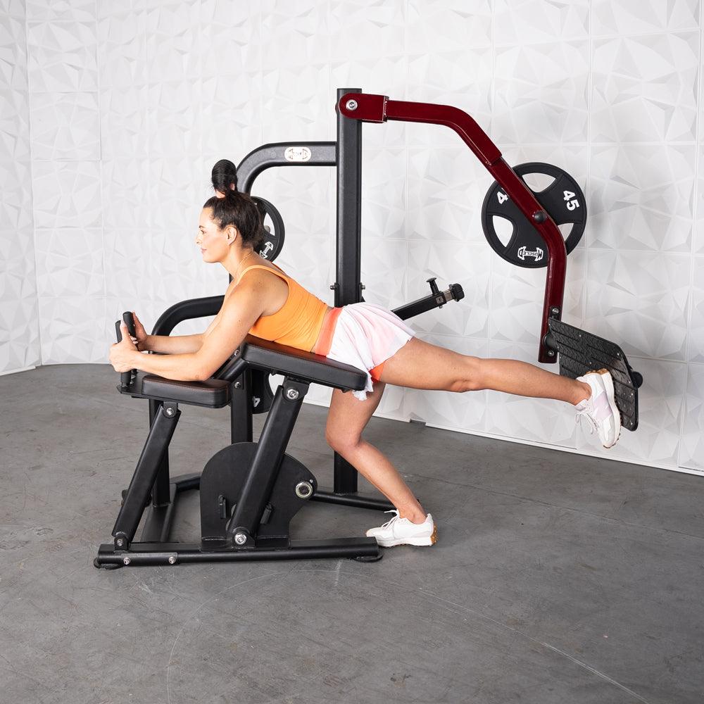 Woman using a black and red plate-loaded glute kickback machine.