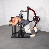 Thumbnail for Man using a plate-loaded glute kickback machine, lying face down on the pad, pushing with his leg.