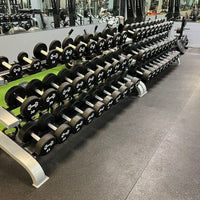 Thumbnail for Rows of black urethane dumbbells with white weight numbers on a gym rack.