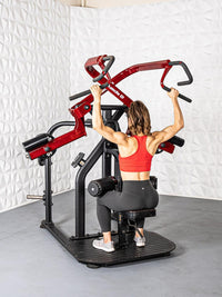 Thumbnail for Woman in red top and black leggings using a red and black rotary lat pull-down machine.