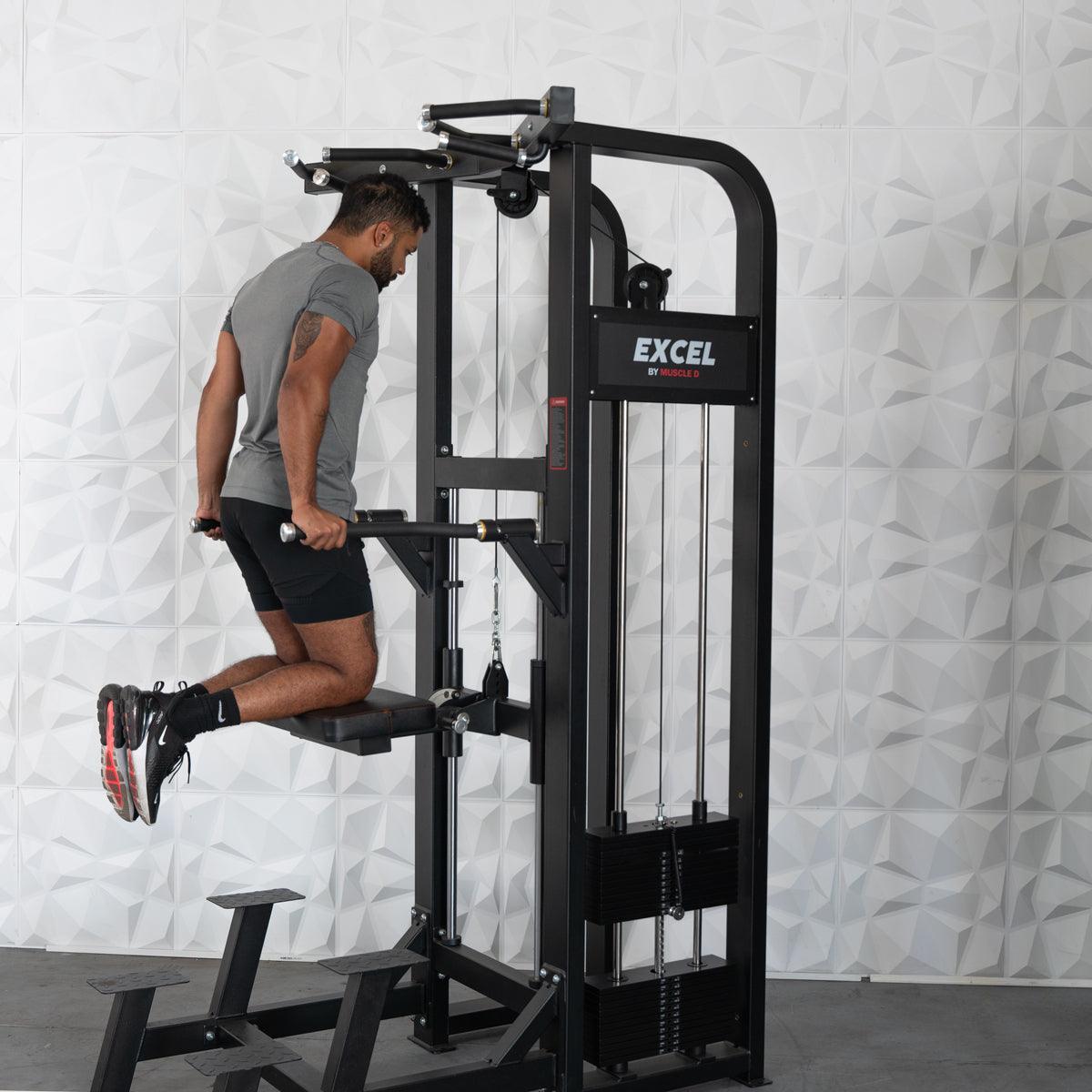 Man performing dips on a black Excel assisted chin/dip combo machine with a white textured wall background.