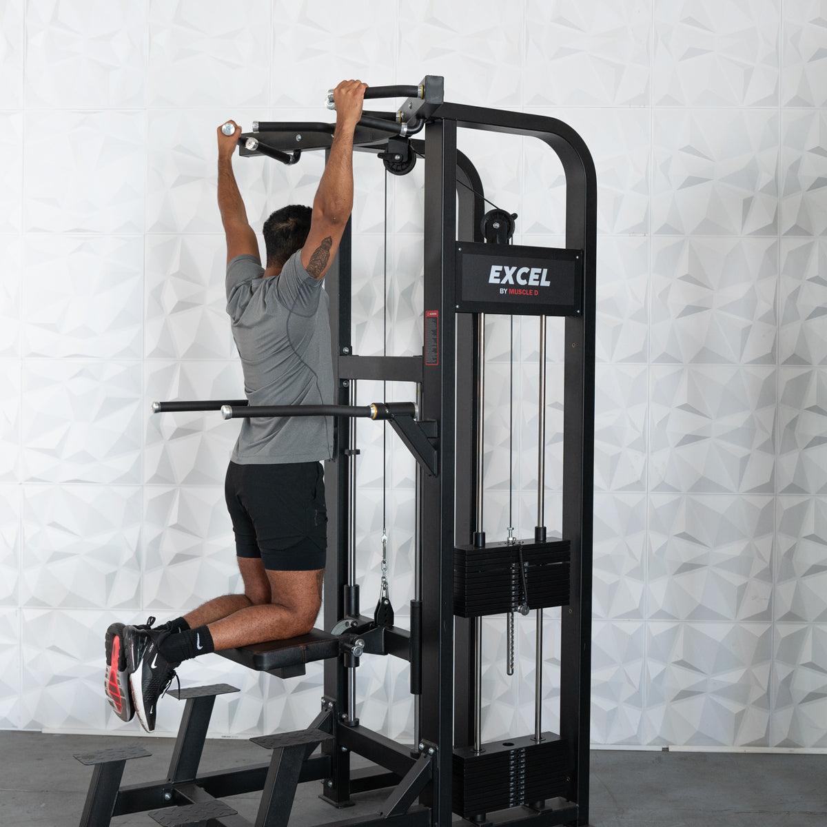 Man performing assisted chin-up on a black Excel chin/dip combo machine with adjustable knee pad.