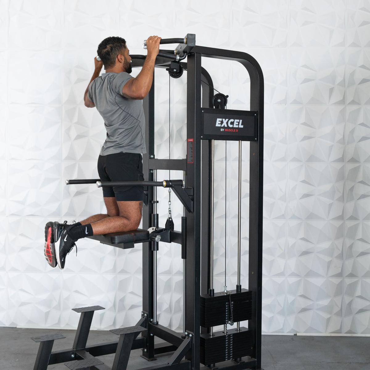 Man performing an assisted chin-up on a black Excel chin/dip combo machine with a collapsable knee pad.