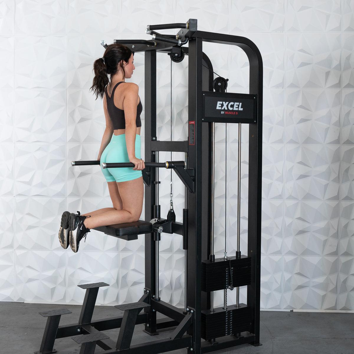 Woman performing assisted dips on a black Excel chin/dip combo machine with a collapsable knee pad.