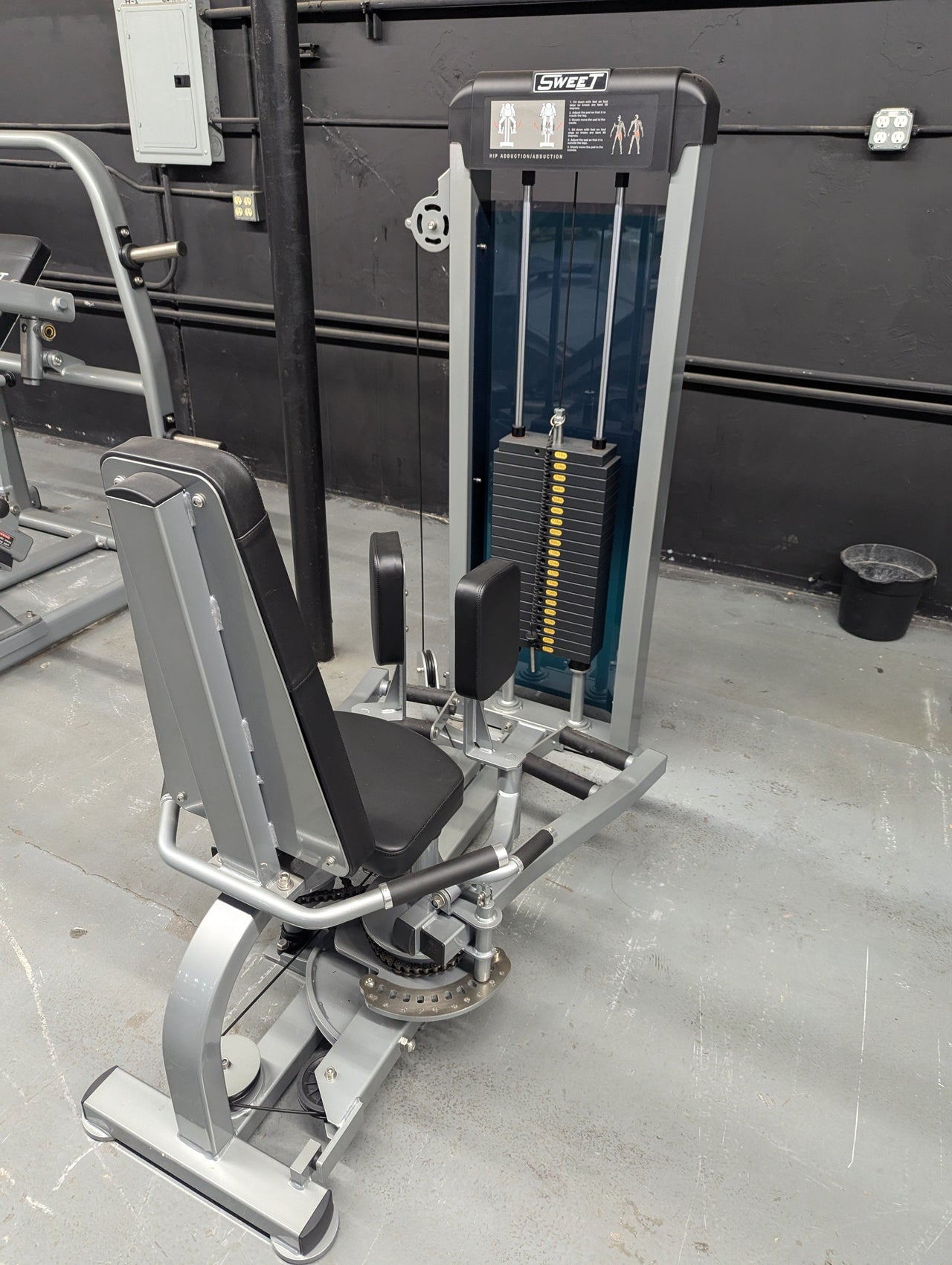 Gray and black gym machine for inner and outer thigh exercises with a weight stack.
