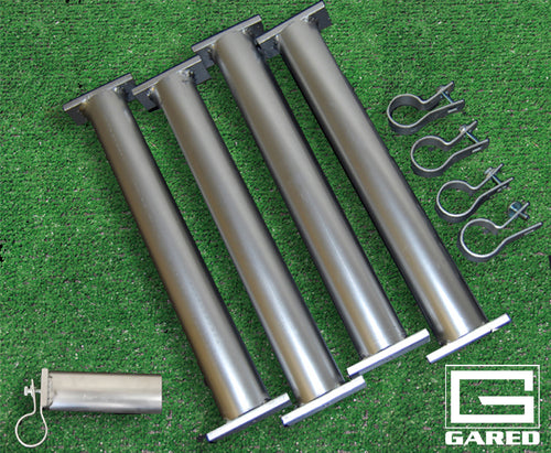 Four metal goal anchors with flat bases, four clamps, and one pin on green turf.