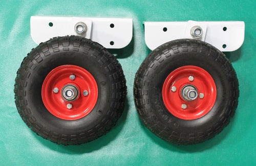 Two black wheels with red hubs and white mounting brackets on a green surface.