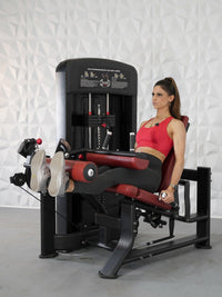 Thumbnail for Woman in red top using a black and red leg extension and curl machine.