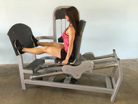 Thumbnail for Woman using a gray seated leg press machine with black footplate and seat.