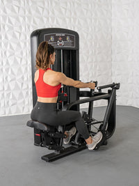Thumbnail for Woman in red top and black leggings using a black seated row machine in a gym.