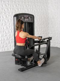 Thumbnail for Woman in red top and black leggings using a black seated row machine.