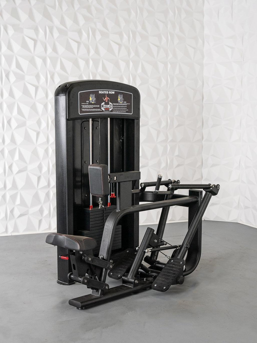 Black seated row machine with weight stack, seat, footrests, and handles on a gray floor.