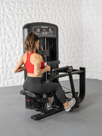 Thumbnail for Woman in red top and black leggings using a seated row machine, back to camera.