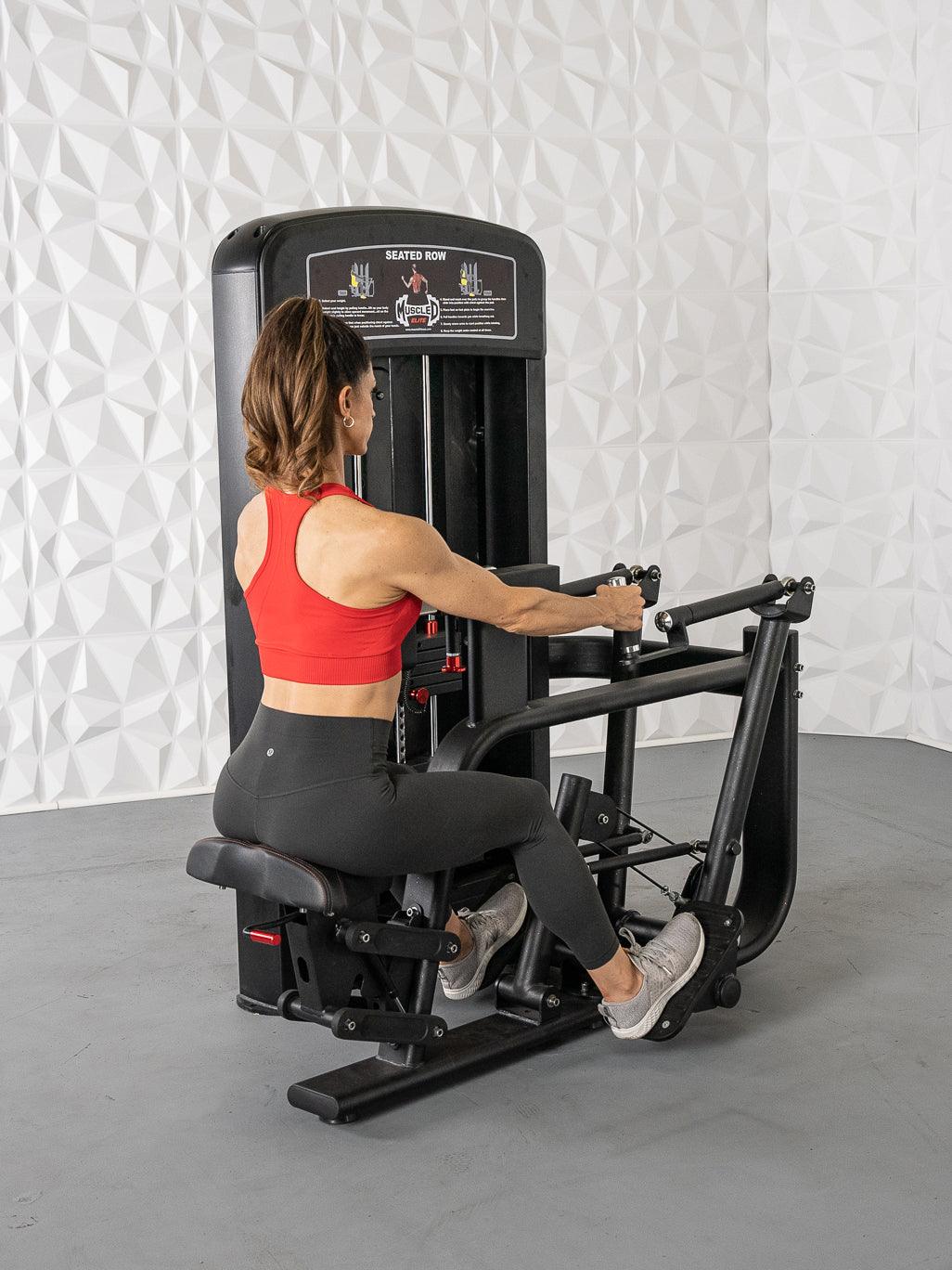 Woman in red top and black leggings using a black seated row machine in a gym.