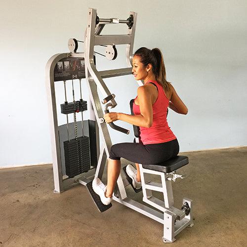 Woman in red tank top using a seated row machine with weight stack.