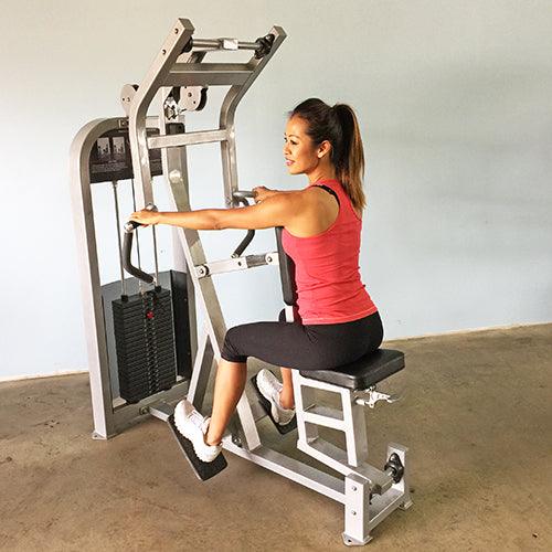 Woman in red tank top and black leggings using a seated row machine.