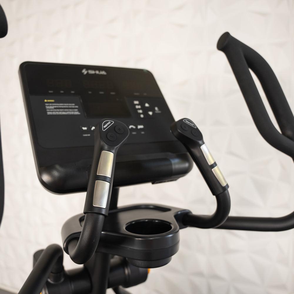 Close-up of a black commercial elliptical machine's console, handlebars, and cup holder.
