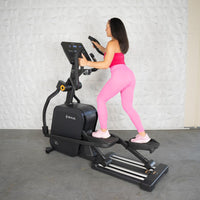 Thumbnail for Woman in pink activewear using a black commercial-grade elliptical cross trainer.
