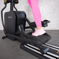 Thumbnail for Person in pink leggings and sneakers using a black elliptical machine.