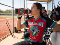 Thumbnail for Softball player in red jersey drinking from a custom black and red water bottle with a team logo.