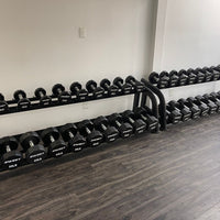 Thumbnail for Two black 2-tier dumbbell racks filled with black hex dumbbells on a dark wood floor.