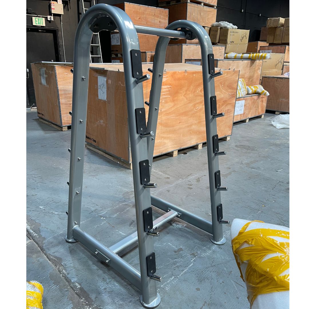 Gray barbell rack with multiple hooks for weight plates, in a warehouse setting.