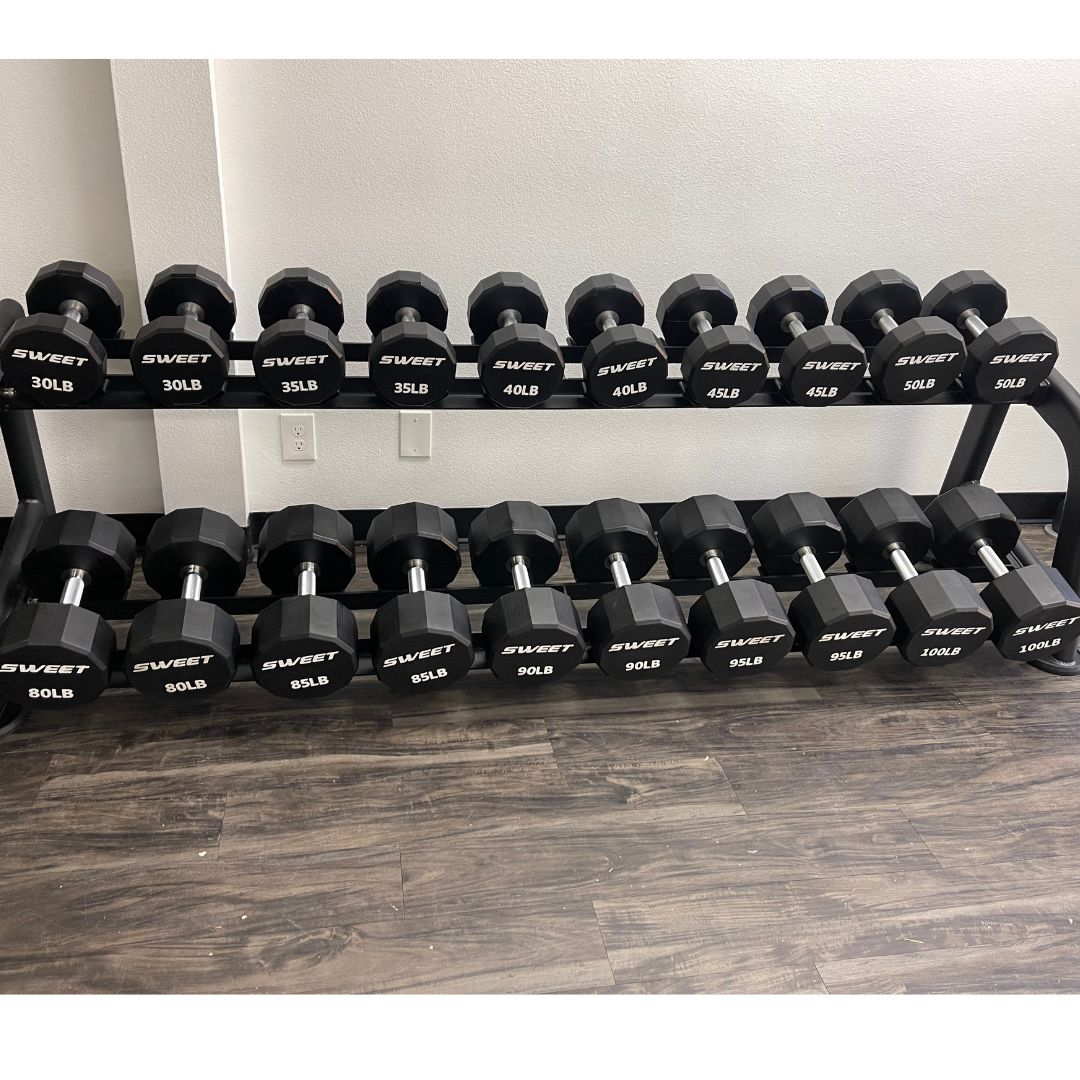 Black Sweet dumbbells from 30lb to 100lb on a two-tier rack.