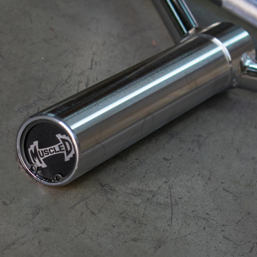 Close-up of a chrome trap bar handle with a "MUSCLED" logo on the end cap.