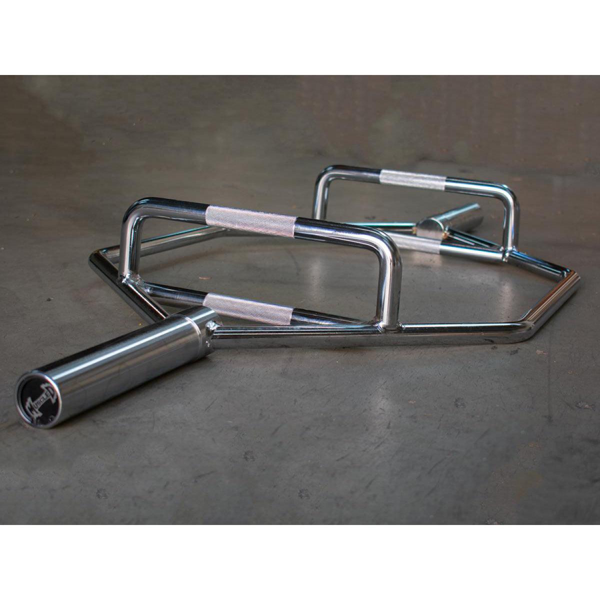 Heavy-duty chrome trap bar with knurled handles on a gray floor.