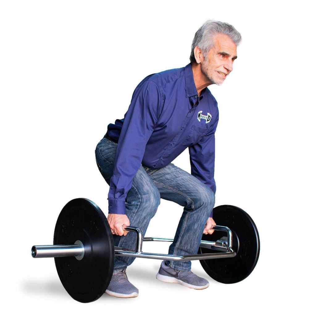 Man in blue shirt and jeans lifting a trap bar with weight plates.