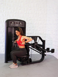 Thumbnail for Woman in red top using a black selectorized triceps press machine.