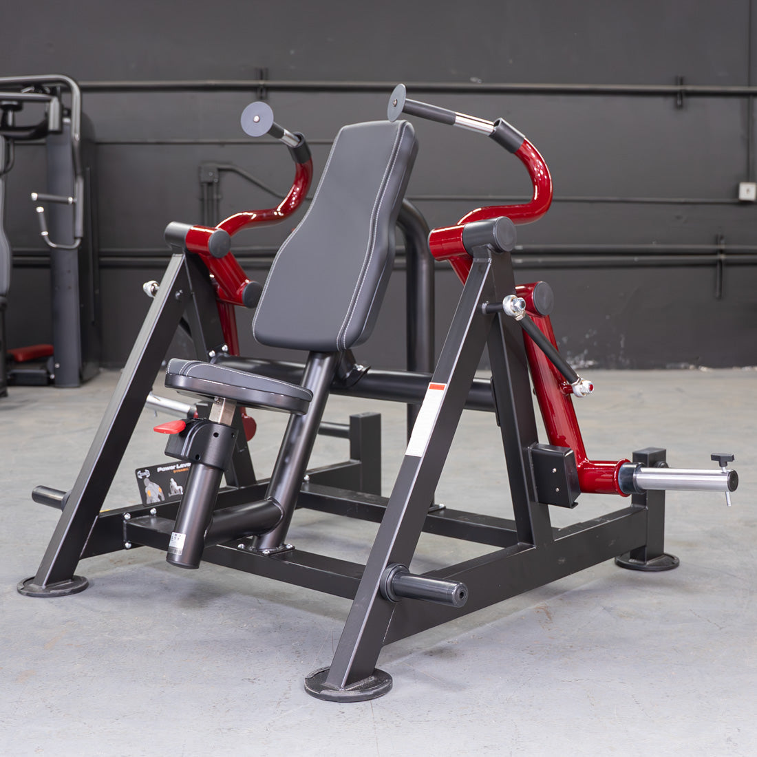 Black and red triceps extension machine with a padded seat and backrest in a gym.