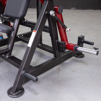 Thumbnail for Close-up of a red and black fitness machine's base with a silver weight plate holder and black footrests.