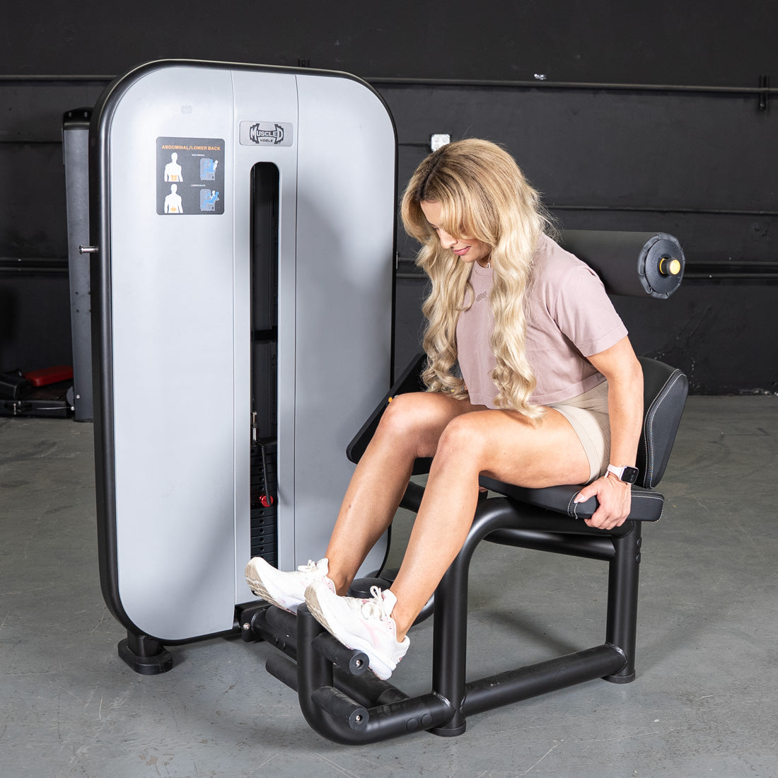 Woman using a gray and black ab/back combo machine for abdominal workouts.
