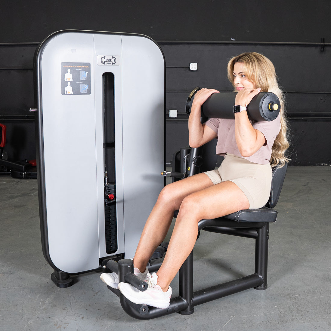 Woman using a Vogue AB/Back Combo machine for abdominal workout, with weight stack visible.