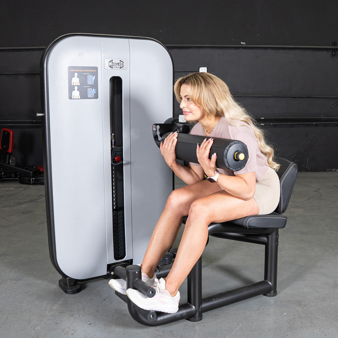 Woman using a gray and black Vogue AB/Back Combo fitness machine for abdominal and back workouts.