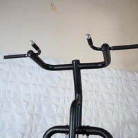 Thumbnail for Close-up of the black metal handles of a chin/dip assist machine, with textured white wall in background.